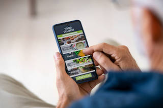 Anziano che utilizza il suo smartphone per ordinare cibo a casa